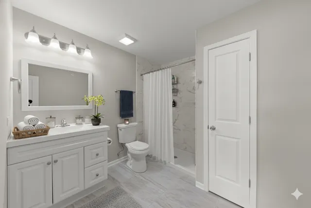 a bathroom with a double vanity sink toilet mirror and shower