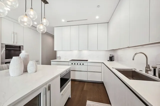 a kitchen with a sink dishwasher a stove and white cabinets with wooden floor