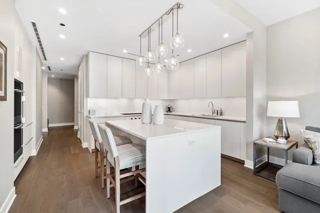 a kitchen with kitchen island a stove a chandelier and a dining table