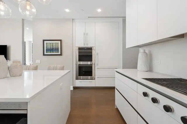 a kitchen with stainless steel appliances white cabinets and a stove top oven