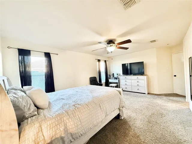 a spacious bedroom with a bed and a flat screen tv