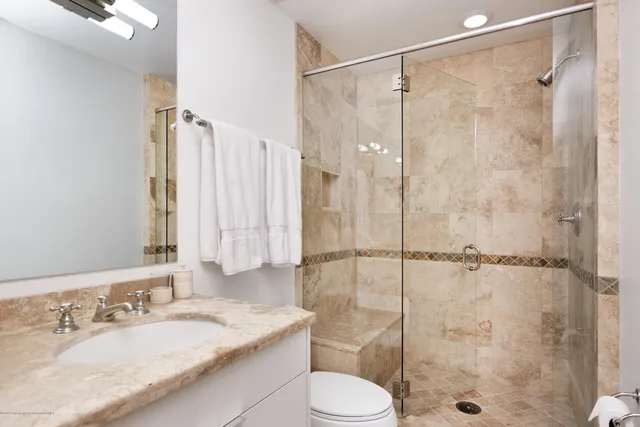 a bathroom with a granite countertop sink a toilet and shower