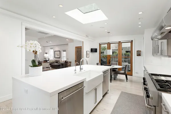 a large white kitchen with sink a counter and chairs