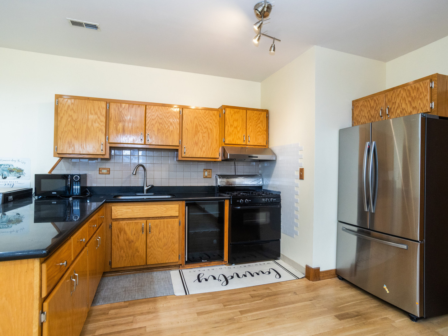 1758 West 35th Street, Unit 3R Chicago, IL 60609 - Photo 3 of 13 a kitchen with stainless steel appliances granite countertop a refrigerator a sink dishwasher a stove and a dining table with wooden floor