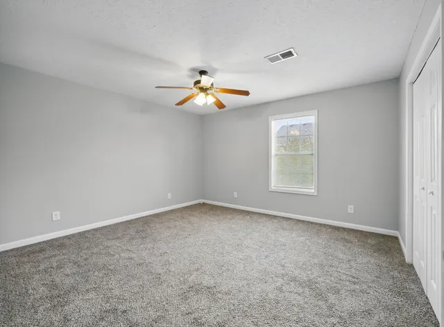 an empty room with a window and a fan