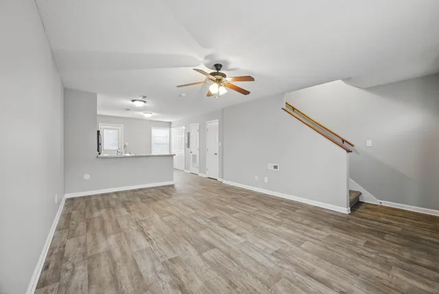 a view of a room with wooden floor and a ceiling fan