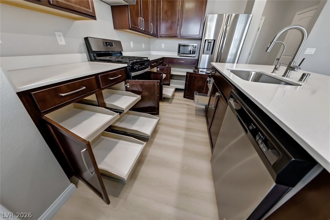 3564 Credere Lane Henderson, NV 89074 - Photo 12 of 40 Kitchen featuring stainless steel appliances, light stone countertops, and dark wood finish cabinetry