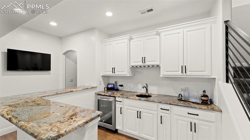 13625 Random Ridge View Colorado Springs, CO 80921 - Photo 27 of 50 Kitchen featuring decorative backsplash, light stone counters, white cabinetry, wine cooler, and recessed lighting