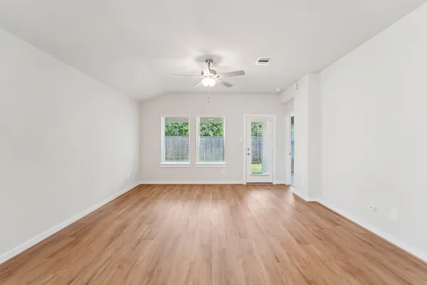 an empty room with wooden floor and windows