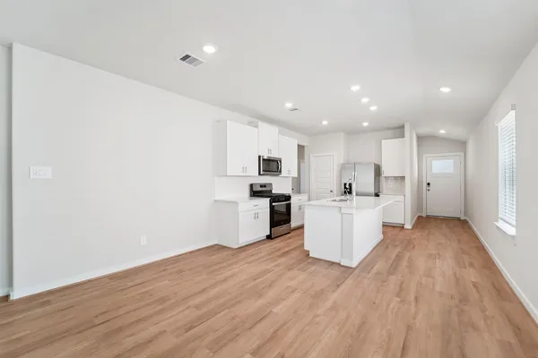 a view of a kitchen with kitchen island wooden floor center island and stainless steel appliances