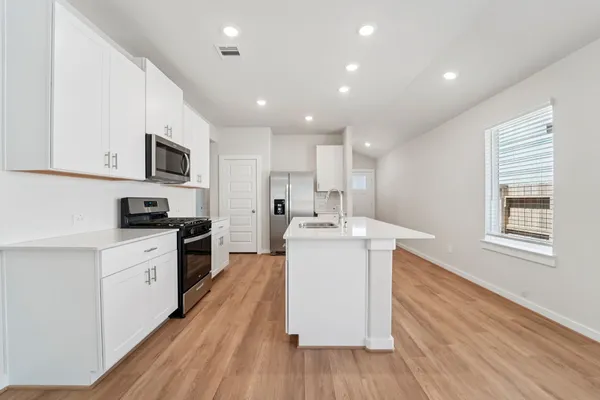 a kitchen with a sink wooden floor and stainless steel appliances
