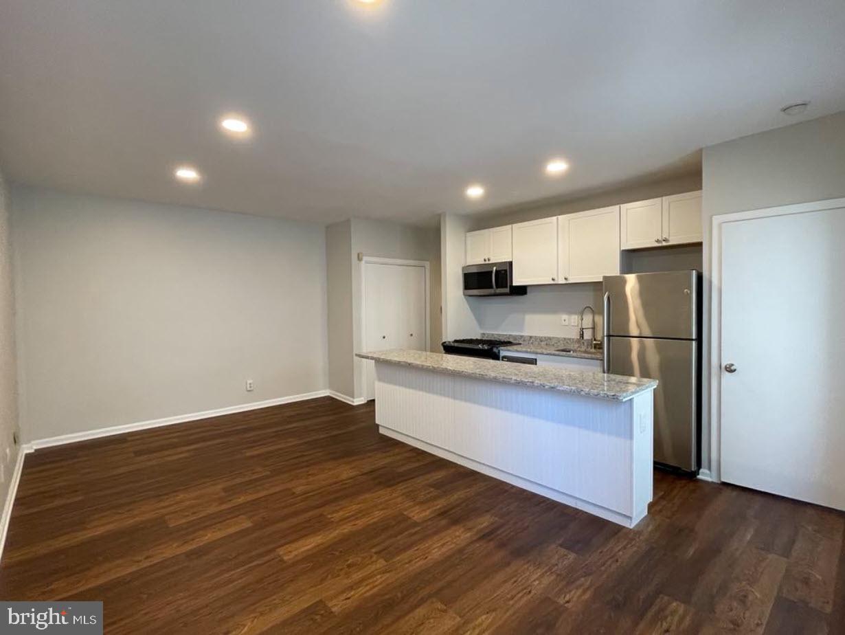 1669 Columbia Road Northwest, Unit 215 Washington, DC 20009 - Photo 11 of 25 a kitchen with stainless steel appliances granite countertop a refrigerator sink and cabinets