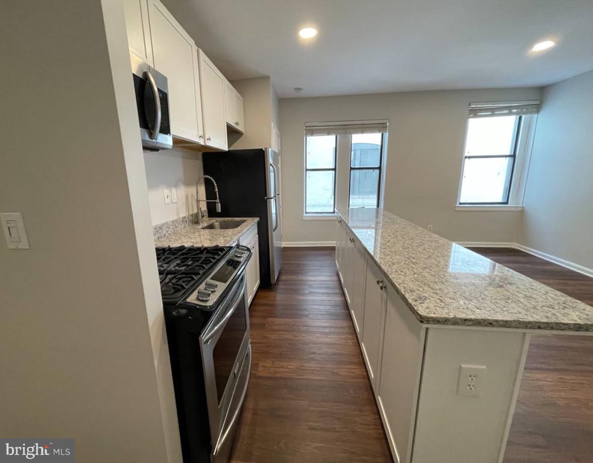 1669 Columbia Road Northwest, Unit 215 Washington, DC 20009 - Photo 16 of 25 a kitchen with granite countertop a stove top oven and sink