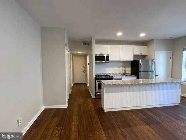 a kitchen with kitchen island a sink wooden floor and stainless steel appliances