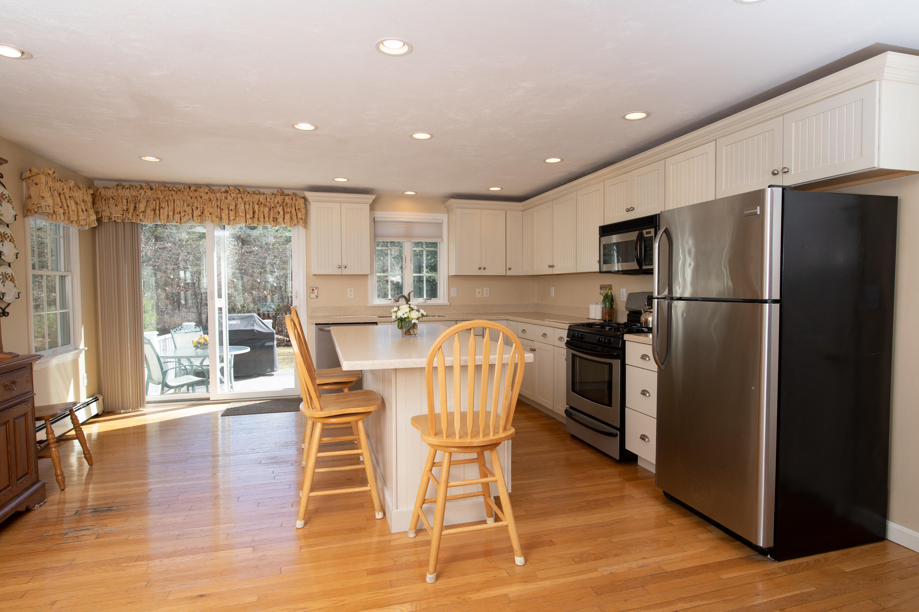 19 Carleton Drive Mashpee, MA 02649 - Photo 12 of 45 a kitchen with stainless steel appliances a dining table chairs refrigerator and cabinets