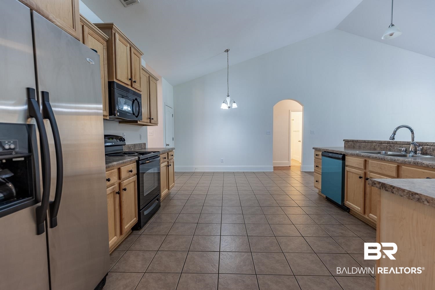101 Normandy Street Fairhope, AL 36532 - Photo 4 of 18 Kitchen featuring black appliances, arched walkways, dark countertops, tile patterned floors, and high vaulted ceiling
