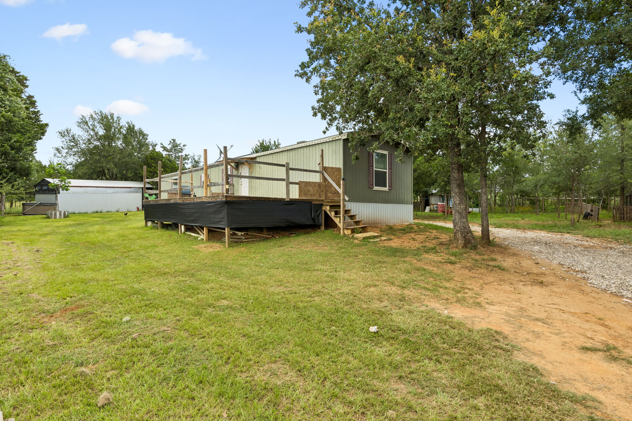 253 North County Line Road, Unit C Elgin, TX 78621 - Photo 2 of 39 A spacious yard surrounds this cozy home, complete with a generous outdoor deck and a practical shed.