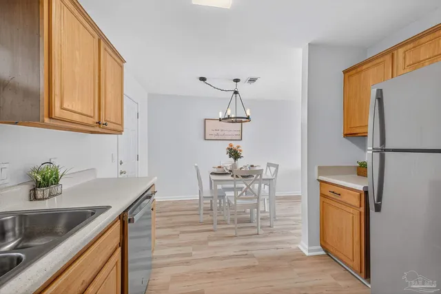 a kitchen with stainless steel appliances granite countertop a sink a stove a dining table and chairs with wooden floor