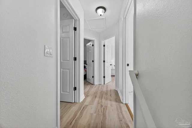 a view of a hallway with wooden floor and a bathroom