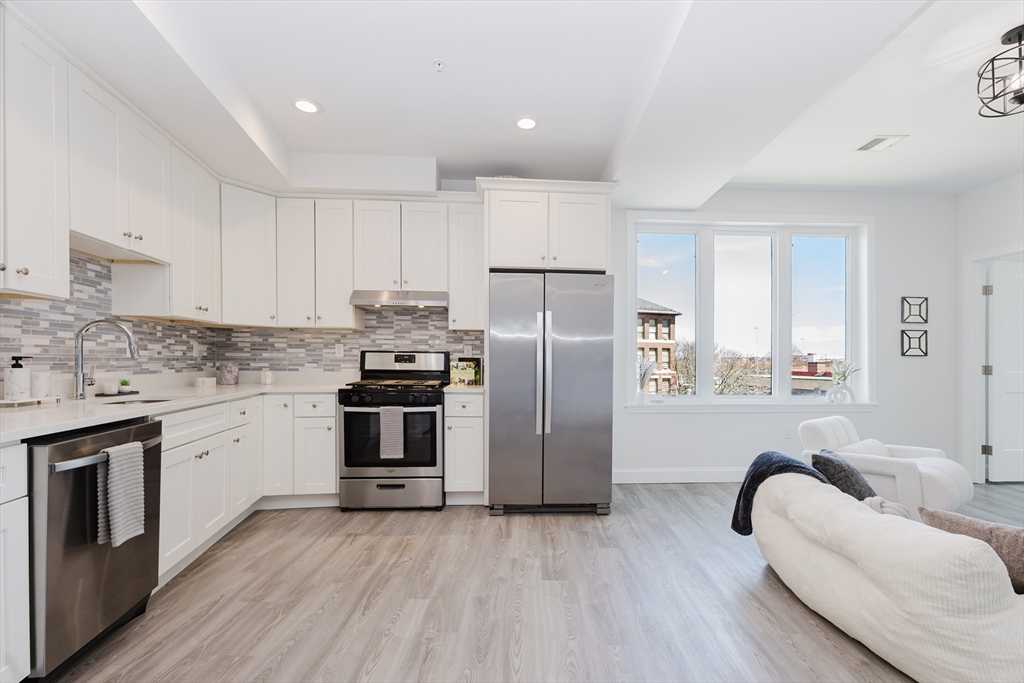 92-94 George Street, Unit 203 Boston, MA 02119 - Photo 5 of 35 a kitchen with stainless steel appliances granite countertop a refrigerator a stove a sink and white cabinets with wooden floor