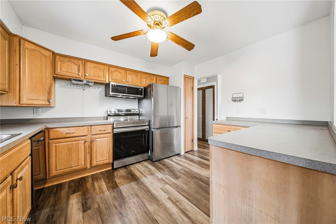 10397 Prouty Road Painesville, OH 44077 - Photo 6 of 32 Kitchen featuring ceiling fan, stainless steel appliances, dark wood finished floors, light countertops, and wood finish cabinetry