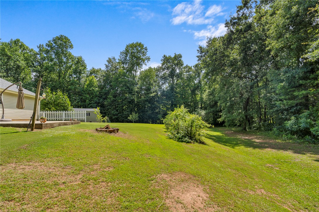167 Mediterranean Avenue Anderson, SC 29621 - Photo 31 of 33 Generous green space offers privacy and potential for outdoor enjoyment, bordered by mature trees and a charming picket fence.