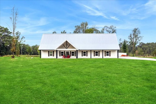 a view of a white house with a big yard and potted plants