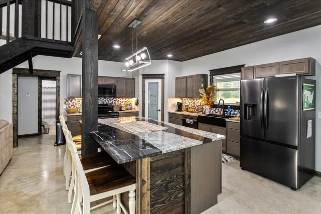 a kitchen with stainless steel appliances granite countertop a table chairs and refrigerator