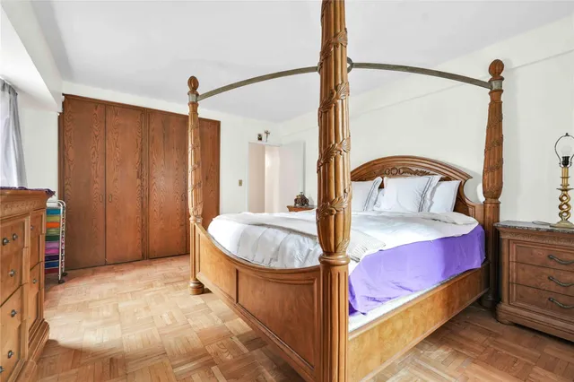 a spacious bedroom with a bed and a dresser with the mirror
