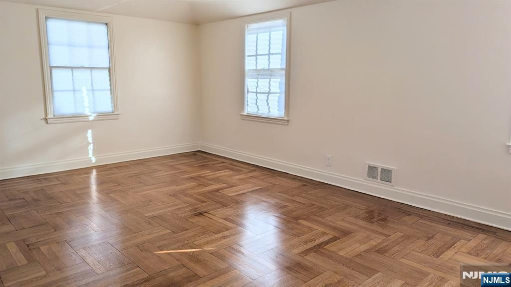 441 New Bridge Road Bergenfield, NJ 07621 - Photo 7 of 11 an empty room with wooden floor and windows