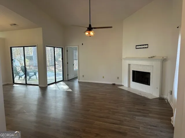 a view of a livingroom with wooden floor a ceiling fan and windows