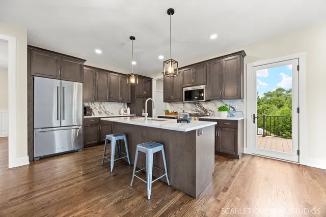 a kitchen with kitchen island granite countertop a stove a refrigerator a oven a sink and a dining table with wooden floor