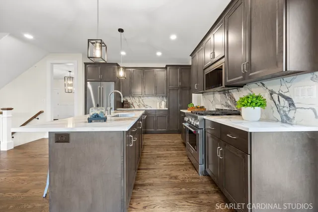 a large kitchen with stainless steel appliances kitchen island granite countertop a sink a stove and a wooden floors