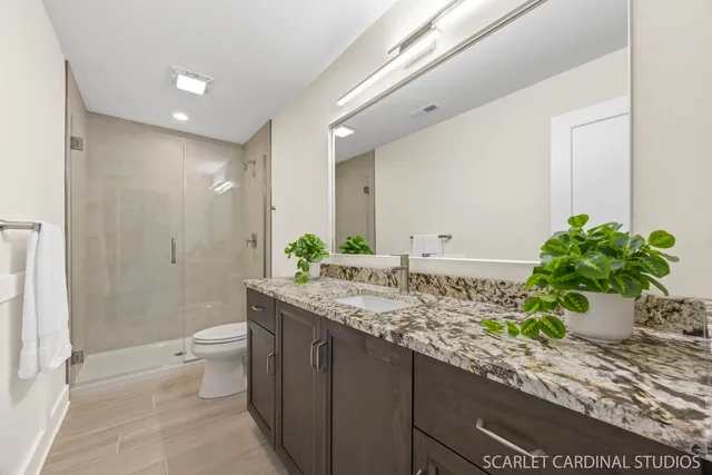a bathroom with a granite countertop sink a toilet and a shower