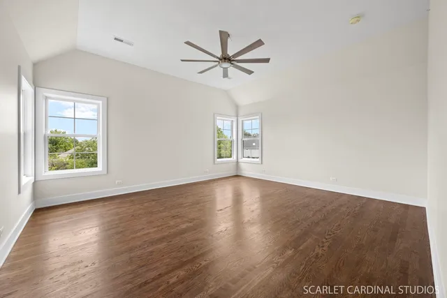 an empty room with wooden floor a ceiling fan and windows