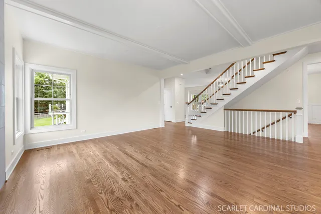 a view of an empty room with wooden floor and stairs