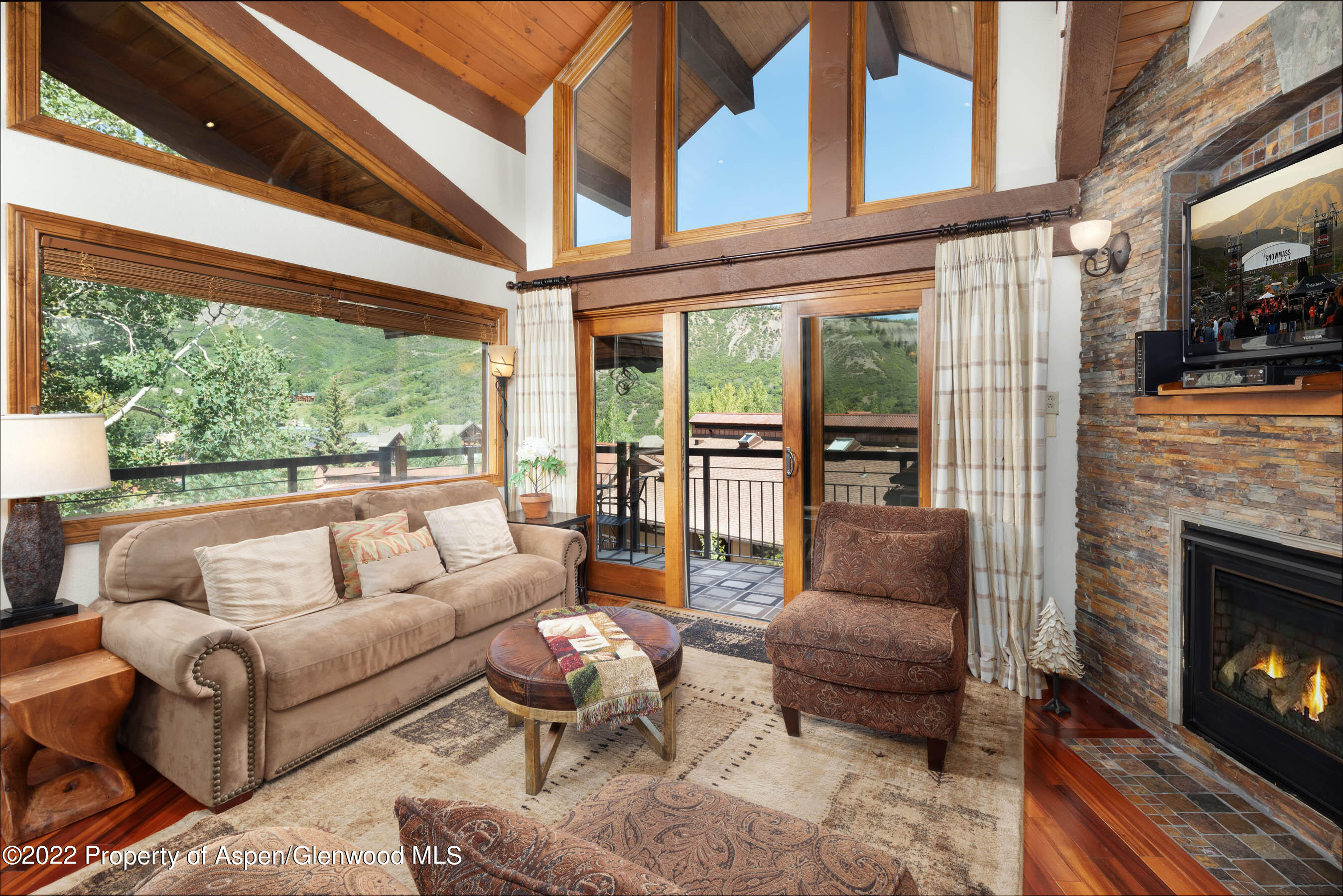 a living room with furniture a fireplace and floor to ceiling windows