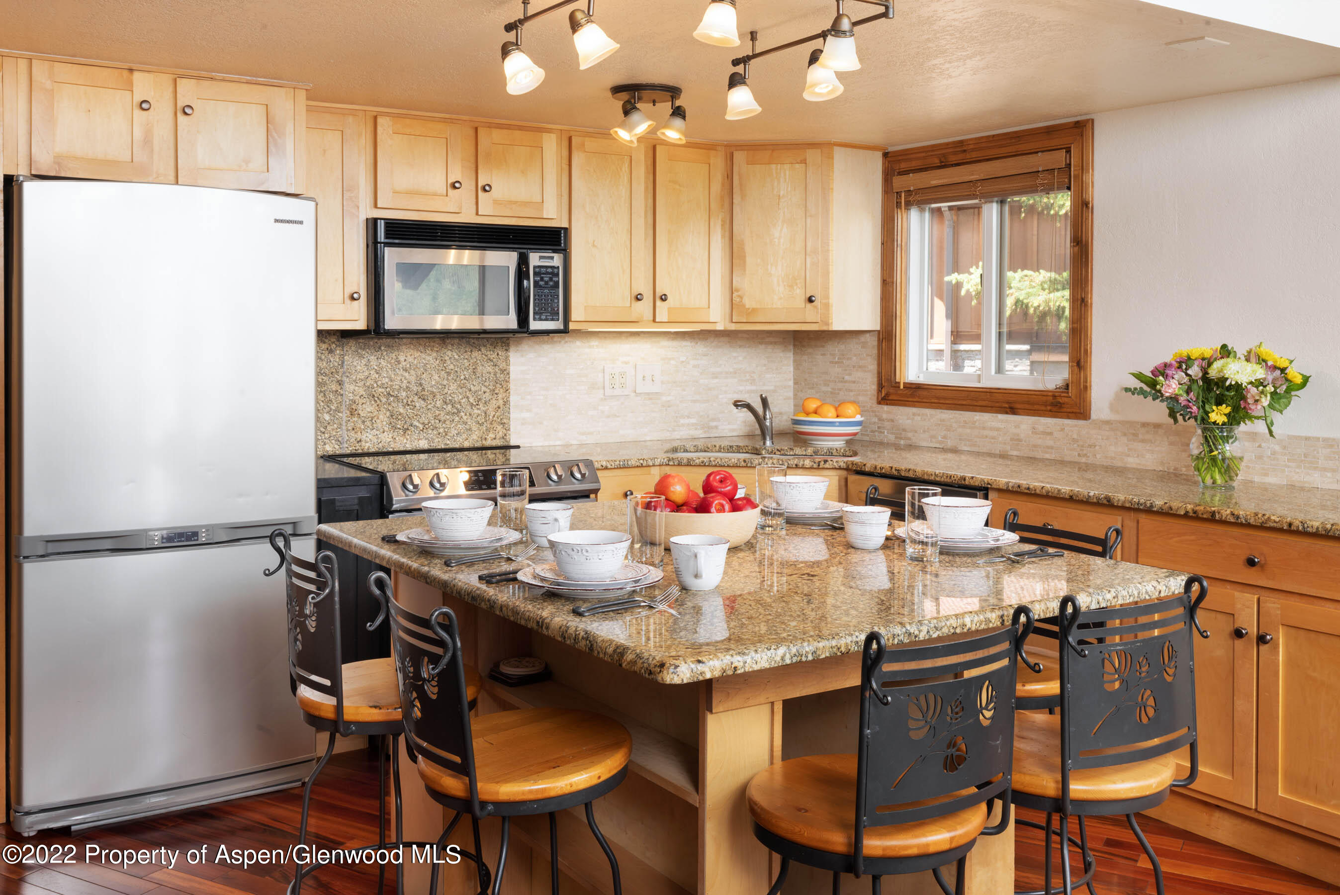 400 Wood Road, Unit 2310 Snowmass Village, CO 81615 - Photo 4 of 18 a kitchen with stainless steel appliances granite countertop a table chairs sink refrigerator and microwave