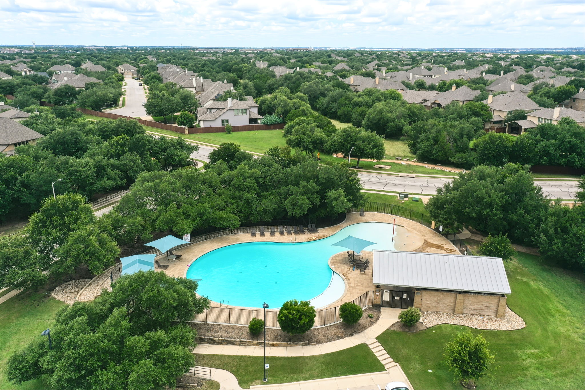 110 Dasher Drive Cedar Park, TX 78613 - Photo 36 of 39 An aerial perspective reveals a vibrant community pool amidst lush greenery and residential rooftops.
