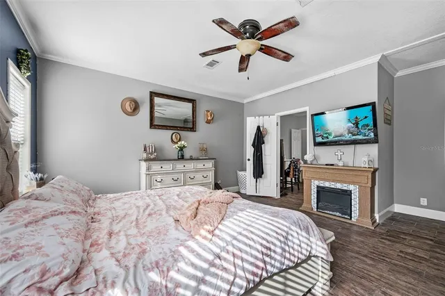 a bedroom with a large bed a flat tv screen and a fireplace