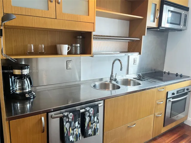 a kitchen with stainless steel appliances granite countertop a sink and a refrigerator