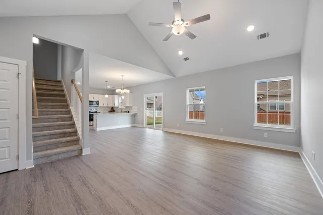 an empty room with wooden floor chandelier and windows