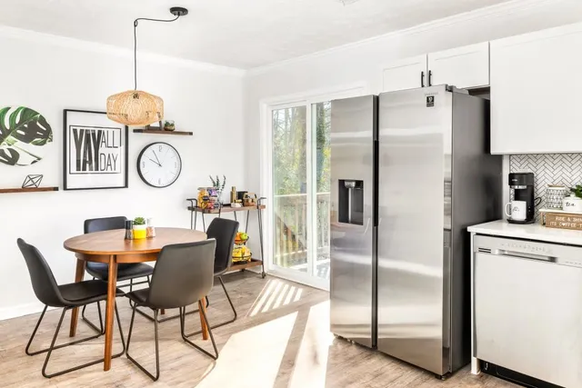 a kitchen with stainless steel appliances granite countertop a dining table chairs refrigerator and cabinets