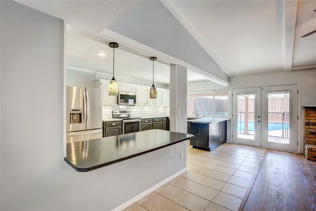 a large white kitchen with a large window and stainless steel appliances