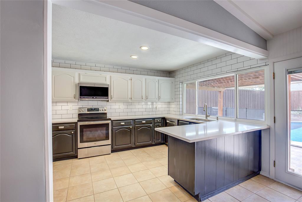 5233 Reed Drive The Colony, TX 75056 - Photo 18 of 40 a kitchen with kitchen island granite countertop stainless steel appliances a stove sink and microwave