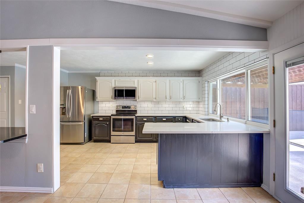 5233 Reed Drive The Colony, TX 75056 - Photo 19 of 40 a large kitchen with stainless steel appliances granite countertop a stove a sink and a refrigerator