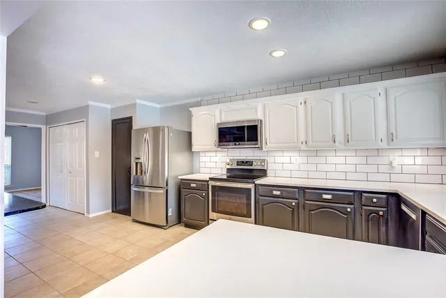 a kitchen with stainless steel appliances granite countertop a refrigerator a sink dishwasher a stove top oven a refrigerator with white cabinets and wooden floor