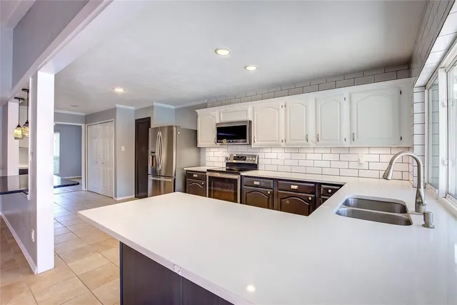 a kitchen with granite countertop a sink a counter top space stainless steel appliances and cabinets