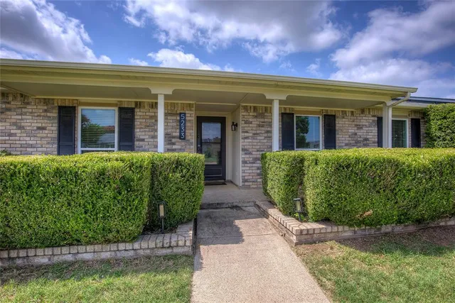 a view of a house with large windows and a flower plants