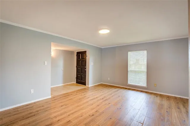 a view of an empty room with wooden floor and window